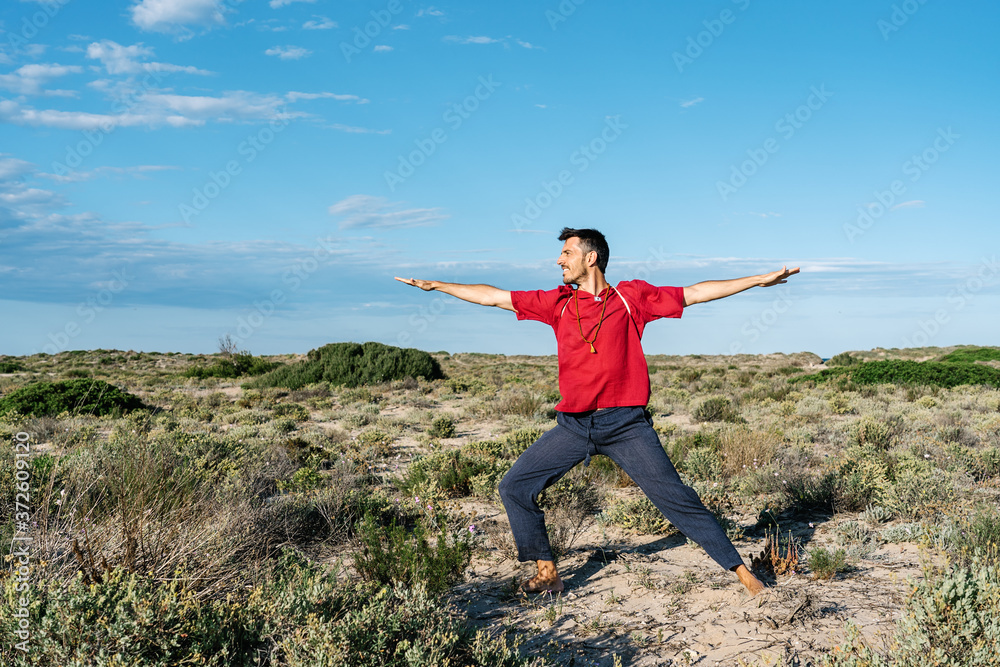 Full length of anonymous man in casual clothes standing on sandy terrain during outdoor yoga training Full length of anonymous man in casual clothes standing on sandy terrain during outdoor yoga training
