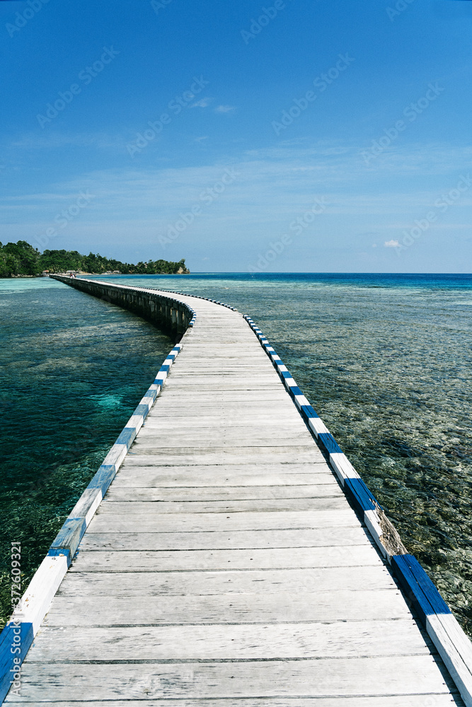 Long wooden embankment going through clear water of sea on sunny day in summer Long wooden embankment going through clear water of sea on sunny day in summer