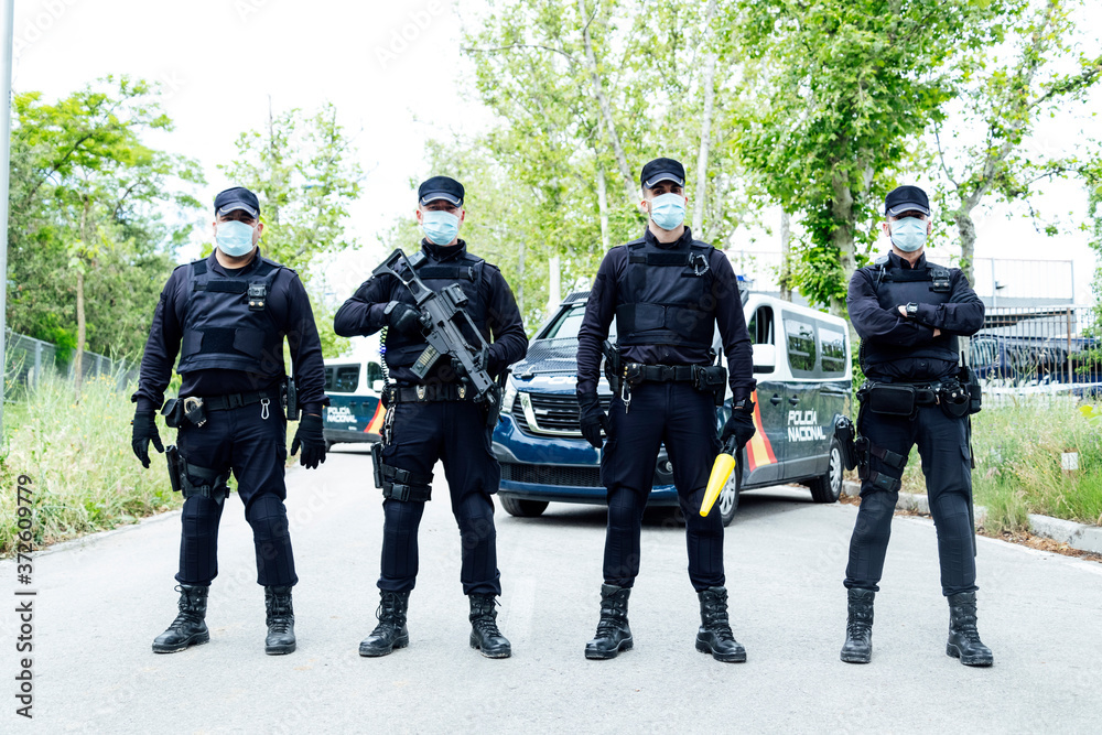 Full body squad of Spanish police officers in protective gears with guns  wearing medical masks during patrolling street Stock Photo | Adobe Stock