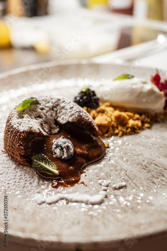 Tasty chocolate lava cake with blueberry and mint placed on plate on cafe table photo