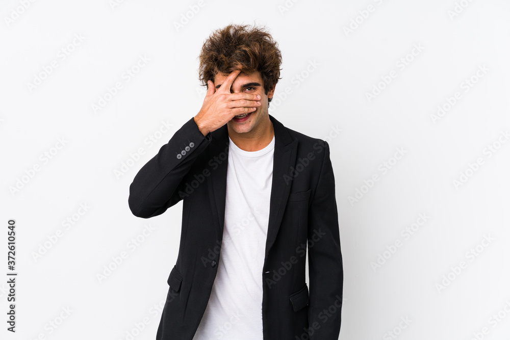 Young caucasian business man against a white background isolated blink at the camera through fingers, embarrassed covering face. Young caucasian business man against a white background isolated blink at the camera through fingers, embarrassed covering face.