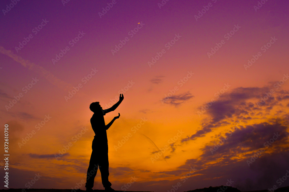 The silhouette of a man raising his hand to the sky
