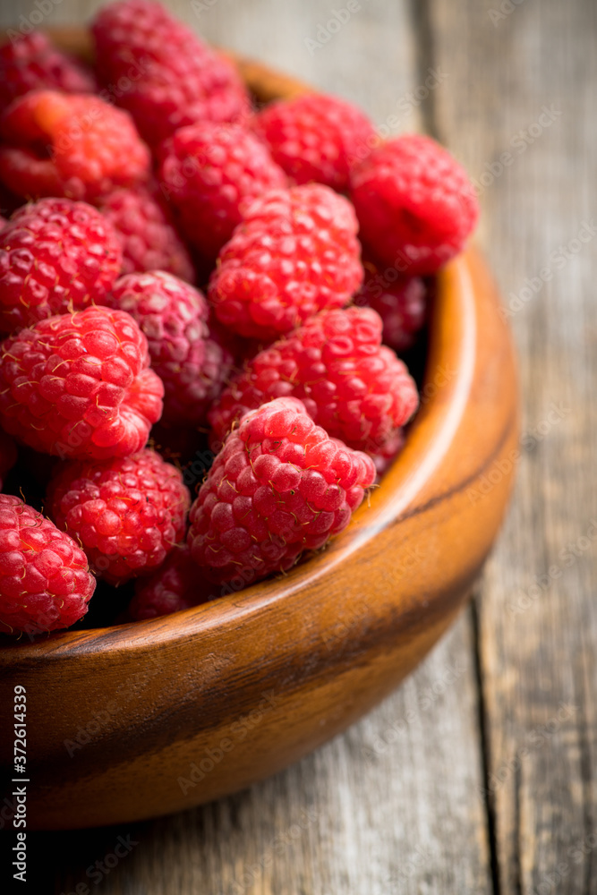 Red ripe raspberry in wooden bowl on the rustic background. Selective focus. Shallow depth of field. Red ripe raspberry in wooden bowl on the rustic background. Selective focus. Shallow depth of field.