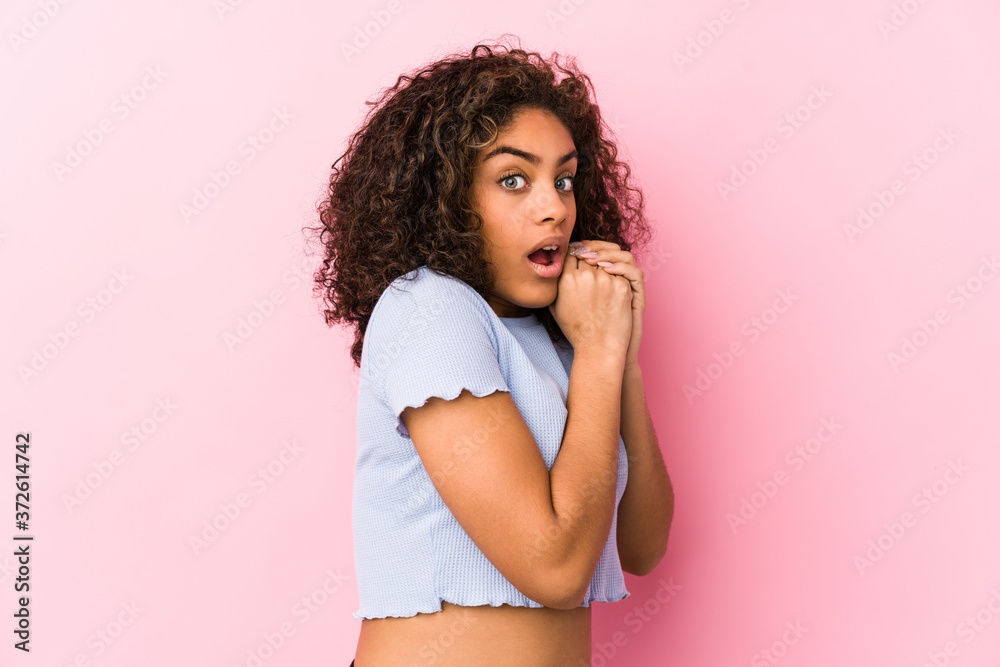 Young african american woman against a pink background scared and afraid.