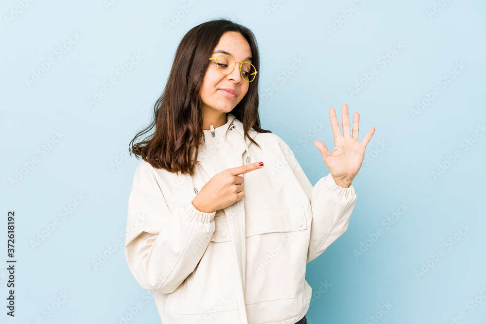 Young mixed race hispanic woman isolated smiling cheerful showing number five with fingers. Young mixed race hispanic woman isolated smiling cheerful showing number five with fingers.