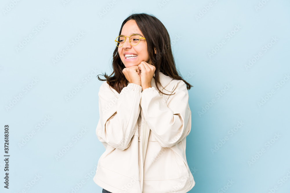 Young mixed race hispanic woman isolated keeps hands under chin, is looking happily aside.