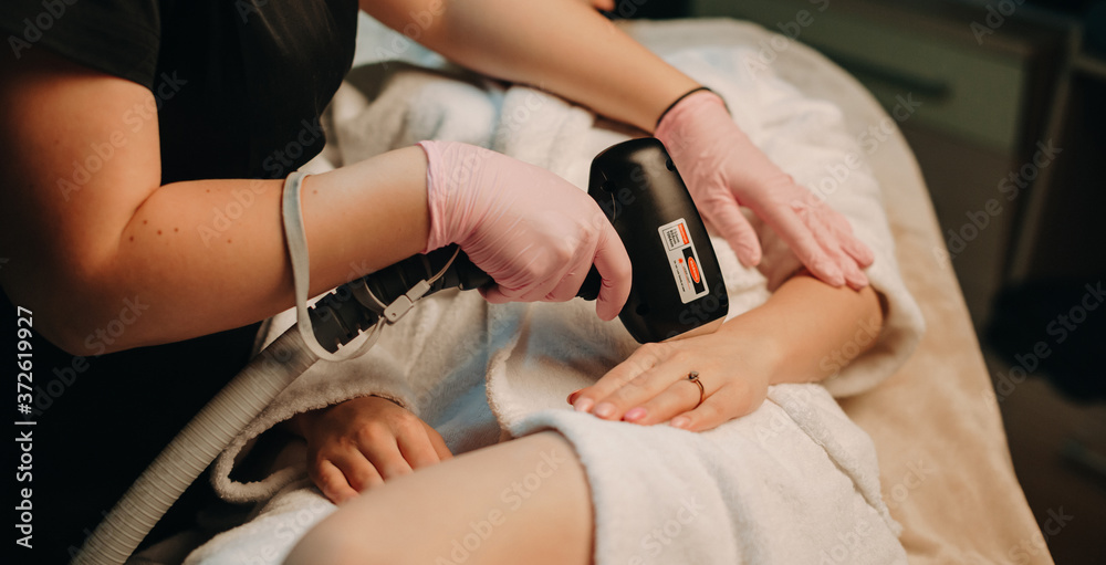 Hand hair removal procedure with laser done by a plump dermatologist working at spa salon Hand hair removal procedure with laser done by a plump dermatologist working at spa salon