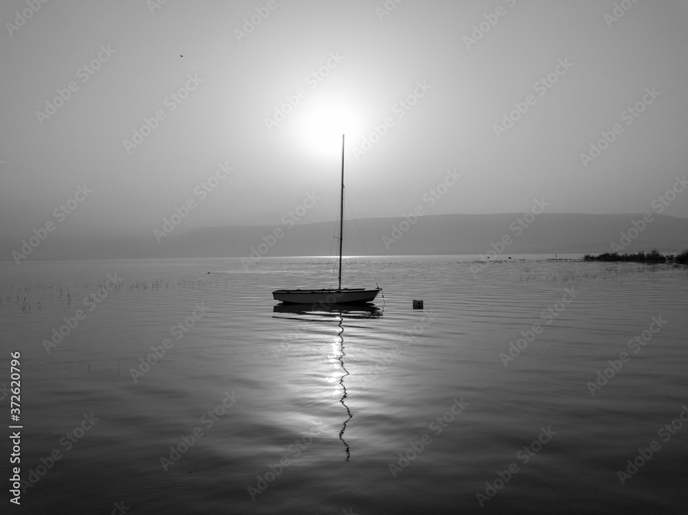 Sunrise over the lake. Boat floating on the calm water under amazing sunset. Sunrise over the lake. Boat floating on the calm water under amazing sunset.