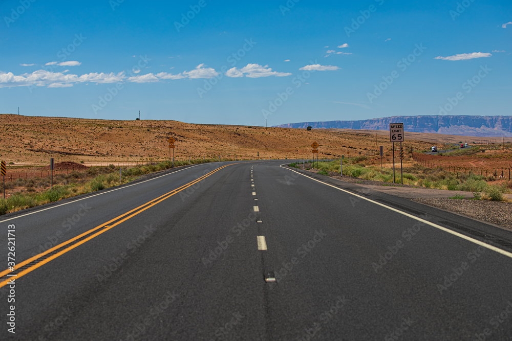 Desert highway at sunset, travel concept, USA. Asphalt highway road and sky sunset clouds landscape. American roadtrip.