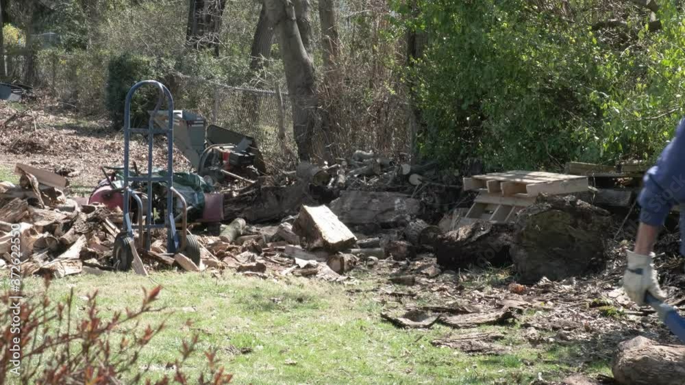 A man pushes a wheelbarrow full of fire wood. A man pushes a wheelbarrow full of fire wood.