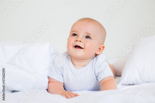 Cute baby boy smiling lies in the bed of the house. bedding for children