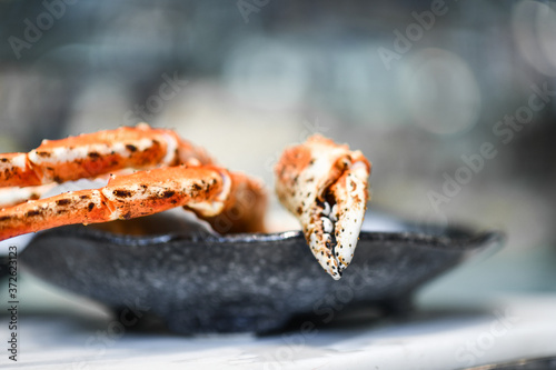 Fotografi Closeup of big fresh tasty crab legs and claw chela in stylish grey bowl