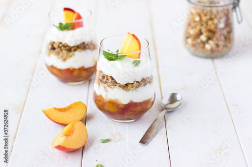 dessert glass of yoghurt, muesli and fruits on a white wooden background. summer, proper nutrition, morning, health, farming, organic food, healthy food concept. free space for text.