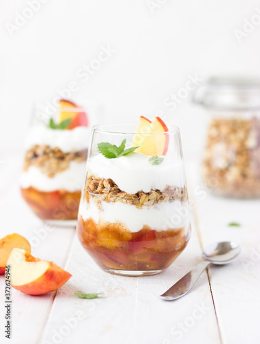 dessert glass of yoghurt, muesli and fruits on a white wooden background. summer, proper nutrition, morning, health, farming, organic food, healthy food concept. free space for text.