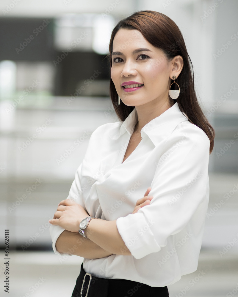 Portrait of a cheerful middle-age businesswoman in business suit standing in the company building with confidence arms crossed. Modern businesswoman in the office with copy space. stock photo. Portrait of a cheerful middle-age businesswoman in business suit standing in the company building with confidence arms crossed. Modern businesswoman in the office with copy space. stock photo.