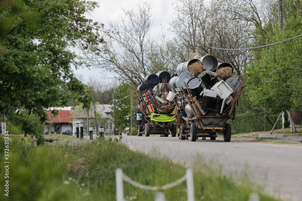 Obraz premium Carriages of Roma people filled with metal rubbish (which they sell later) on a countryside road.