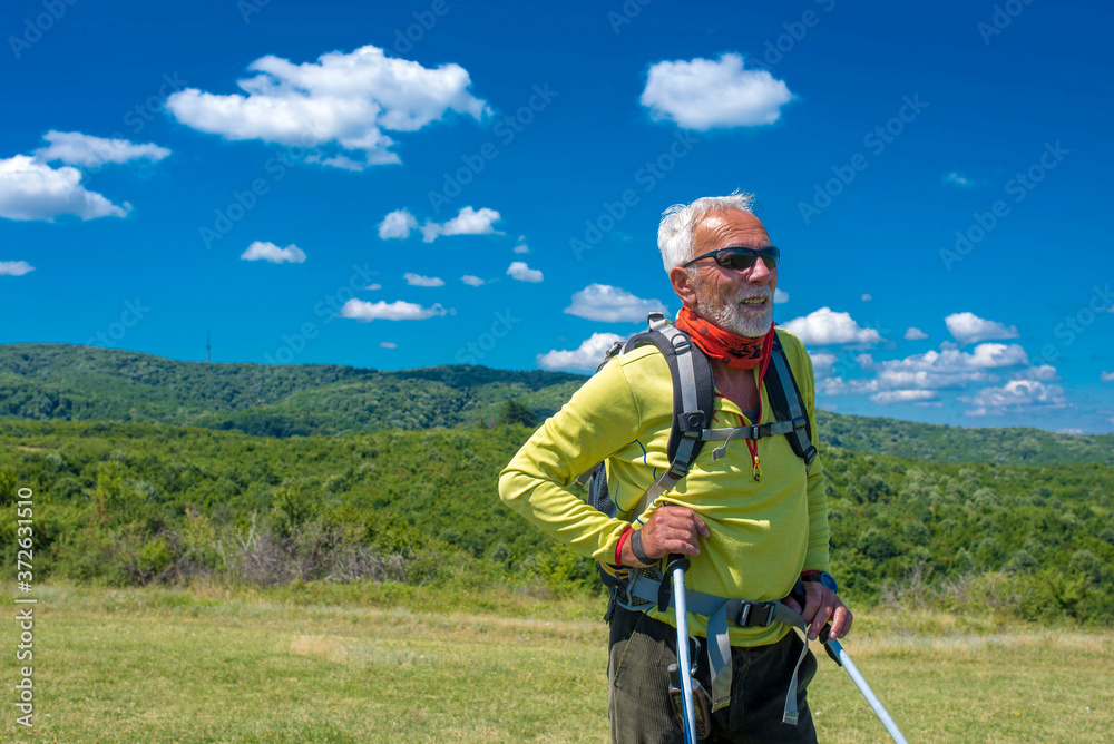 Caucasian senior man hiking in high mountains with beautiful nature landscape in the background