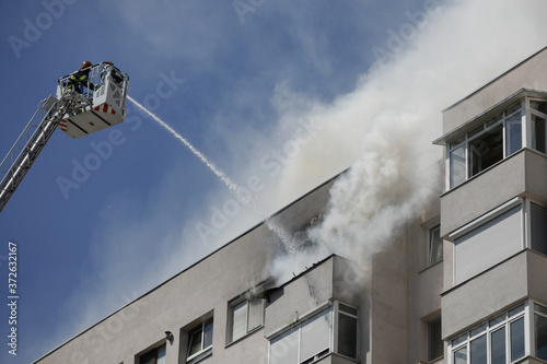 Firefighters try to extinguish a fire that spread across an apartment in a block of flats. photo