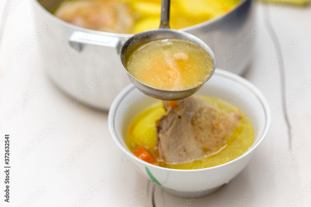 hand pours chicken soup on a white table hand pours chicken soup on a white table