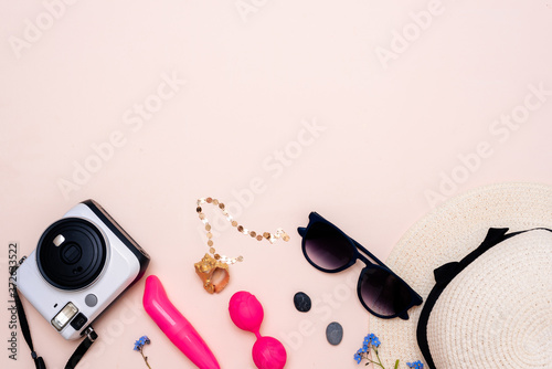 summer travel accessories. women's set of adult toys, camera, hat, glasses on a light background. space for your text photo
