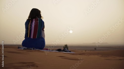 Young woman watching the desert sunset in Morocco. Saraha desert photo