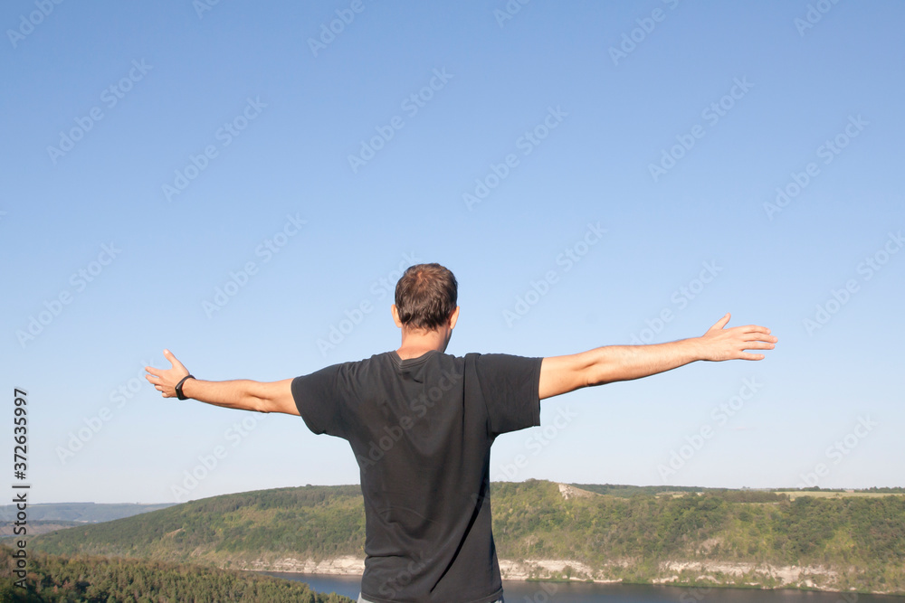 A man with arms outstretched against the backdrop of the sky and nature. Recuperation, enjoyment, balance concept A man with arms outstretched against the backdrop of the sky and nature. Recuperation, enjoyment, balance concept