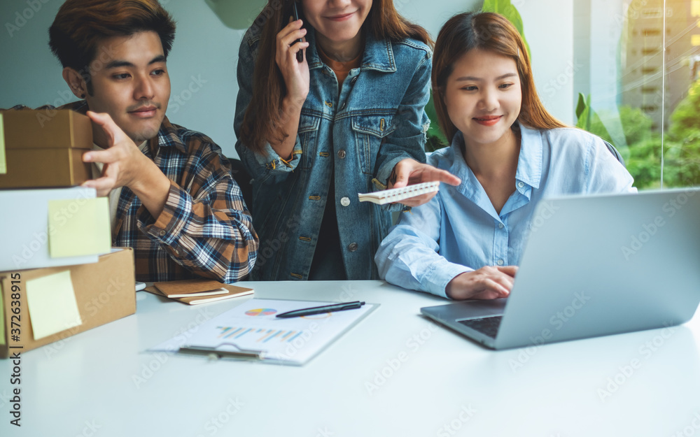 A group of young entrepreneur confirming and checking orders from customer on the phone for online shopping and delivery concept A group of young entrepreneur confirming and checking orders from customer on the phone for online shopping and delivery concept