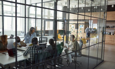 Business meeting. Group of happy smiling multiracial business people discussing project, working together while sitting in a conference room in the modern coworking space