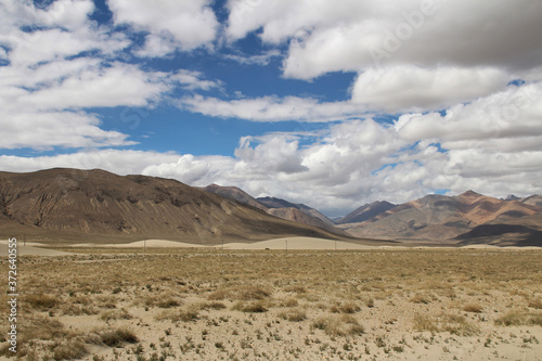 View of the mountain and sand dune with dirt road in a sunny day, Tibet, China