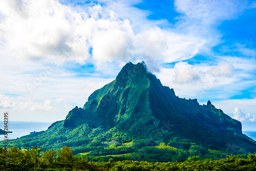 Moorea, French Polynesia: 09/03/2018: Total lanscape of the colorful main mountain in Moorea, everywhere is green and a blue sky