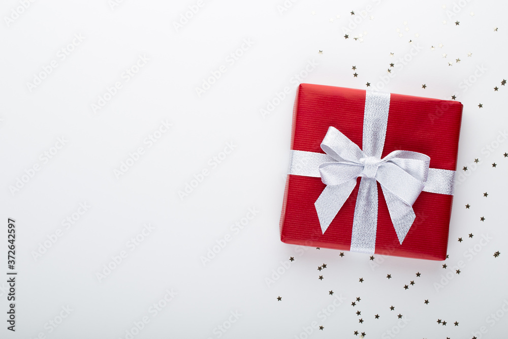 Fototapeta premium Gift or present box and stars confetti on color table top view. Flat lay composition for birthday, mother day or wedding.