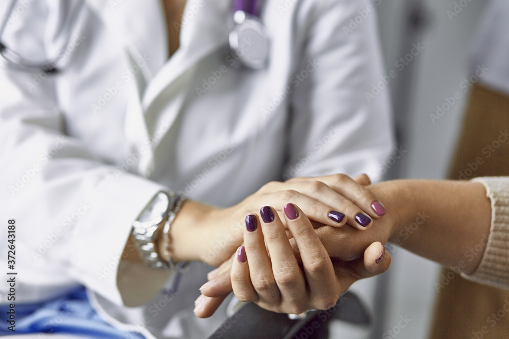 Obraz premium Woman doctor calms patient and holds hand
