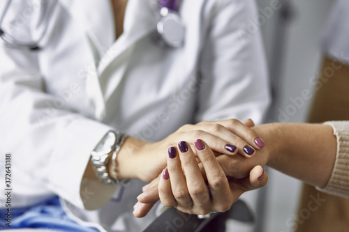 Woman doctor calms patient and holds hand