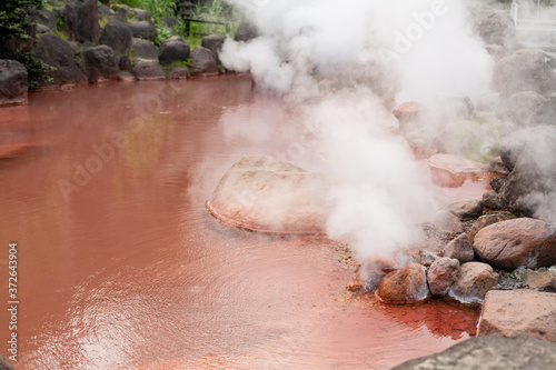 natural red colored hot spring with rising steam in beppu city, oita pref, japan photo