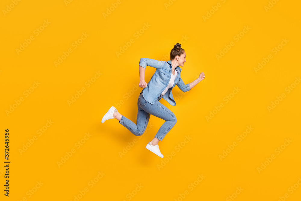 Full body profile photo of attractive teen lady jumping high up running race marathon excited to win rushing wear casual denim shirt sneakers pants isolated yellow color background