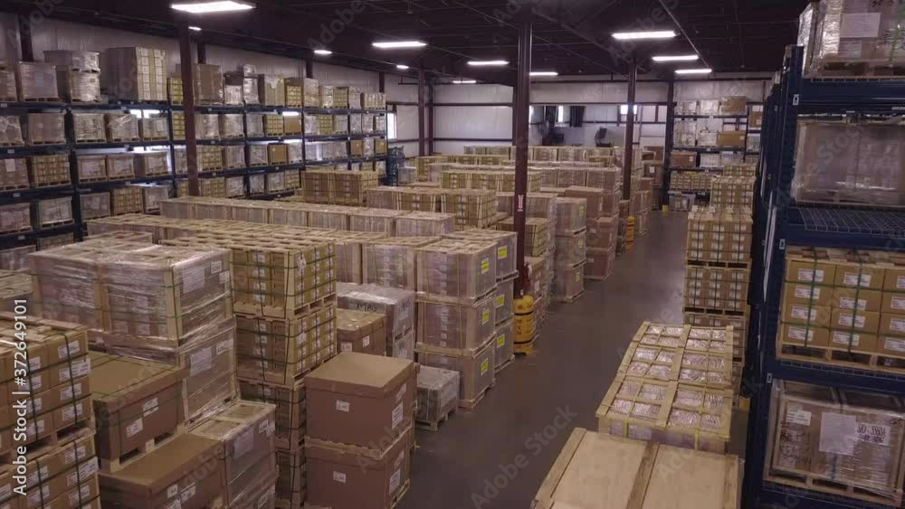 Aerial of boxes stacked on floor and shelves in industrial warehouse