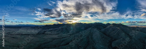 Aerial view and panorama of Arizona mountain ranges during sunset with clouds and sun