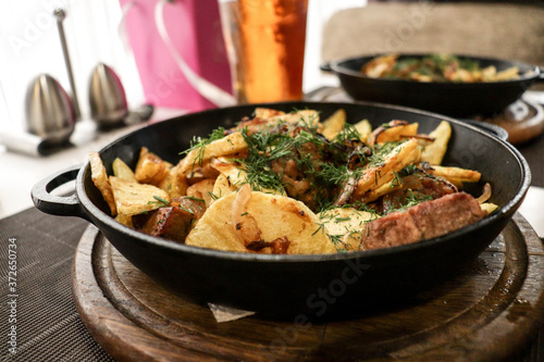 meat with potatoes and vegetables cooked in a pan and glasses with beer