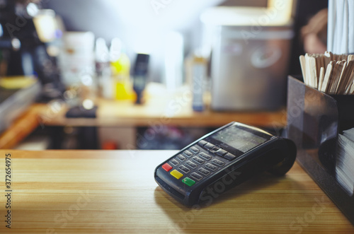 The credit card payment terminal is on the table in coffee shop cafe. Close-up of contactless payment device, card machine