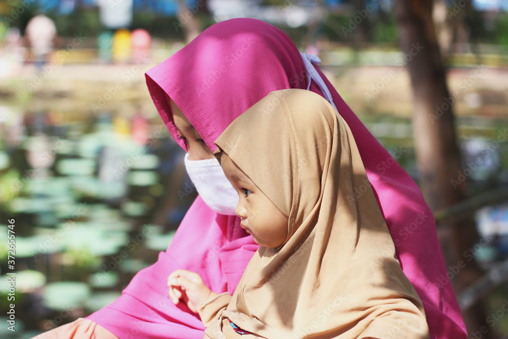 A cute beautiful muslim Indonesian baby girl with her mother in the park