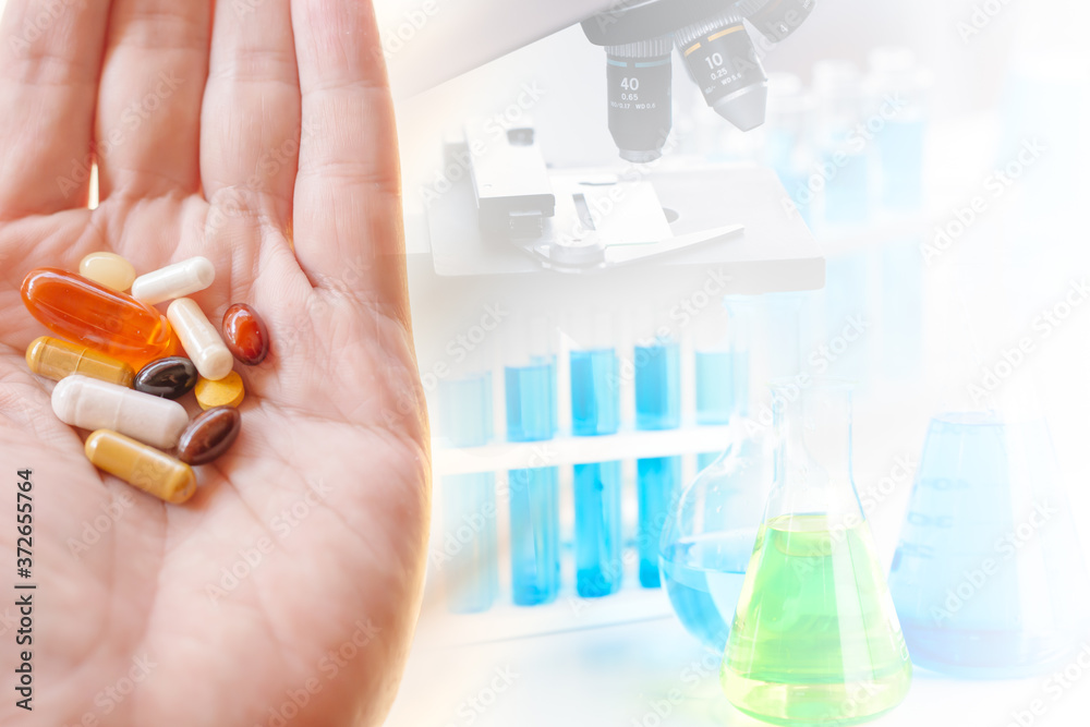 Group of medical pill on hand with science lab medical research on backgroud space for text. Group of medical pill on hand with science lab medical research on backgroud space for text.