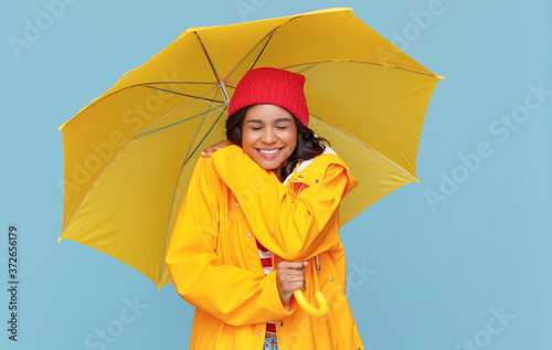 Excited ethnic woman under umbrella.