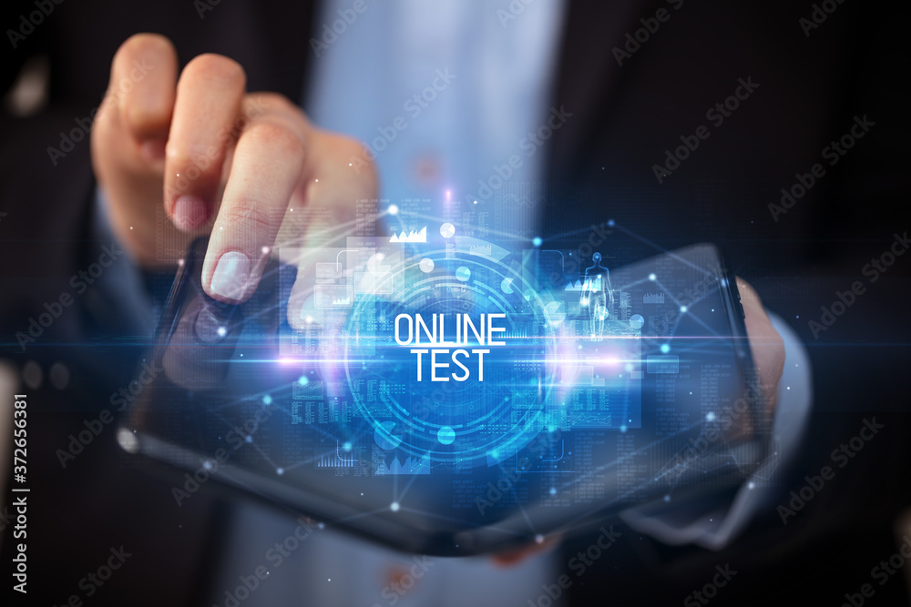 Young man holding a foldable smartphone with ONLINE TEST inscription, educational concept Young man holding a foldable smartphone with ONLINE TEST inscription, educational concept