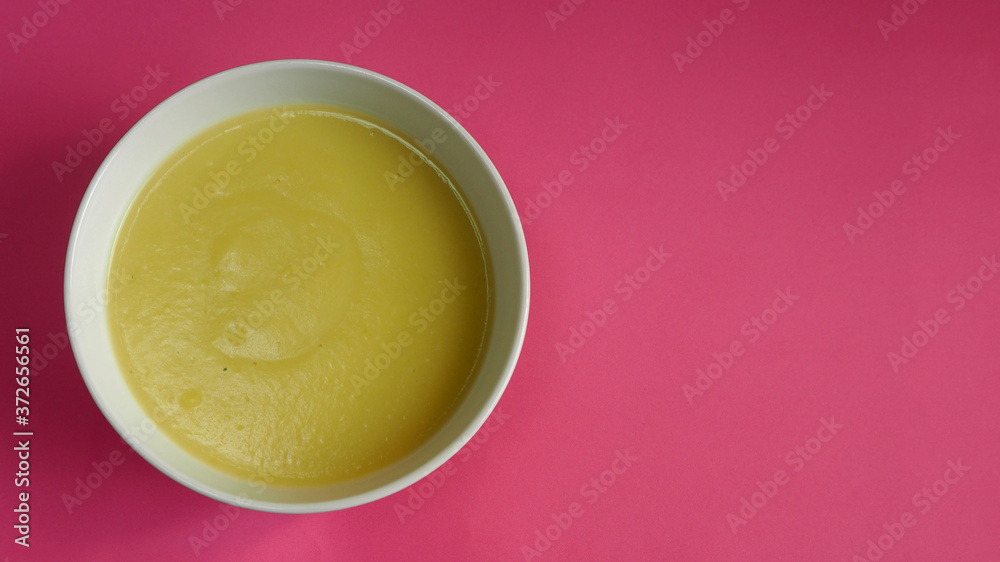 white plate with cream soup of zucchini, potatoes, cream, onions on a pink background top view . cooking gluten-free food at home white plate with cream soup of zucchini, potatoes, cream, onions on a pink background top view . cooking gluten-free food at home