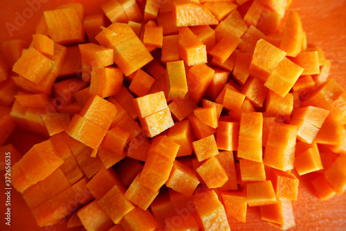 raw orange diced carrots on a plastic orange Board top view . food preparation stage