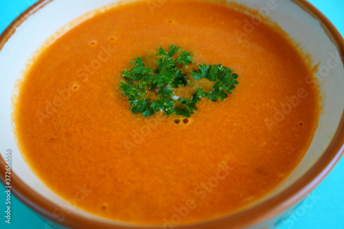 close-up of tomato puree soup with a sprig of green parsley side view . home-made gluten-free food