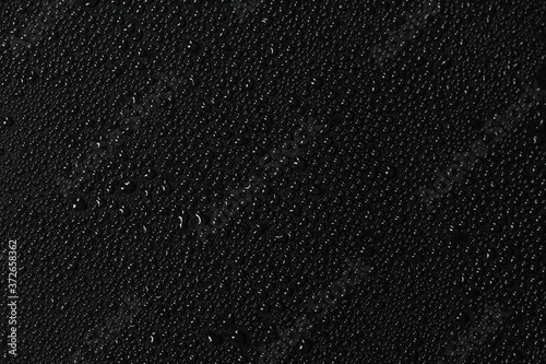 Water droplets on black background. Close-up photo of small water drops on black background.