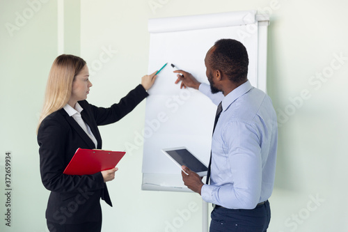Young businessman and woman waiting for departure in airport, work trip, business lifestyle. Man and woman working with flipchart in special conference zone before starting their vacation