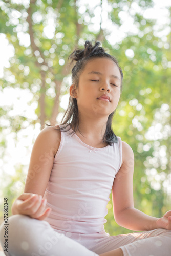 Free Download calmness and relax, female happiness.Horizontal, blurred background. little asian girl meditates while practicing yoga. freedom concept. calmness and relax, child happiness. toned picture healthy life - GFXLoad