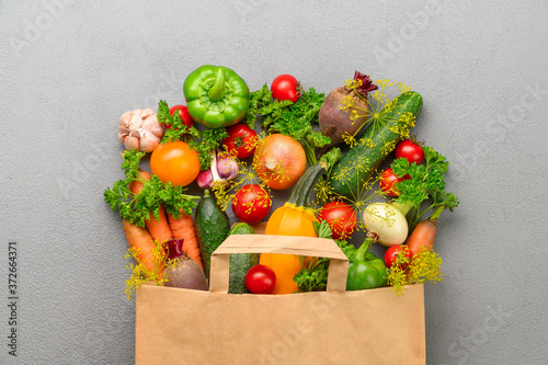 Fototapeta Naklejka Na Ścianę i Meble -  Paper bag of different vegetables on a gray background. Top view. Bag food concept.